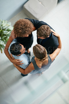 Buy stock photo High angle shot of a group of  businesspeople standing arm in arm in a huddle in a modern office