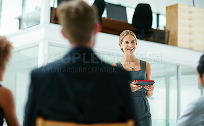 Buy stock photo Shot of a businesswoman holding a digital tablet while giving a presentation to colleagues in a modern office