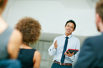 Buy stock photo Shot of a businessman holding a digital tablet while giving a presentation to colleagues in a modern office