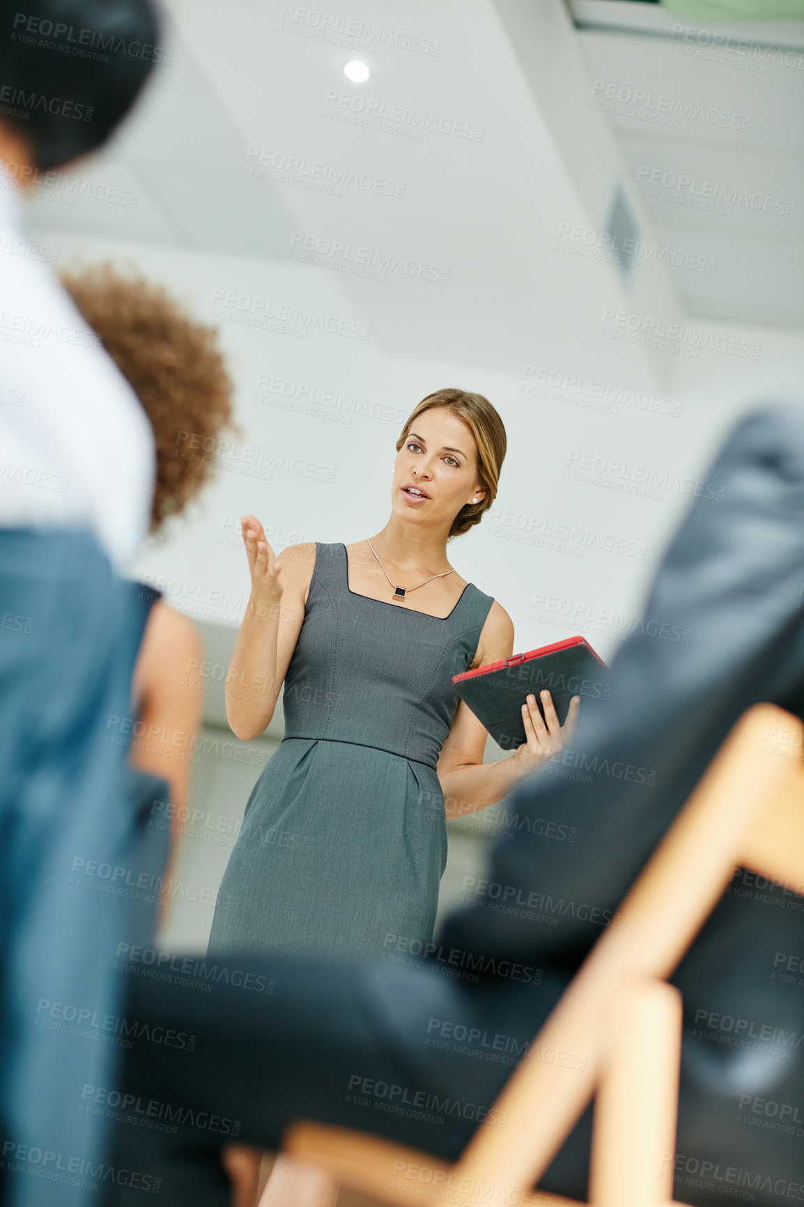 Buy stock photo Shot of a businesswoman holding a digital tablet while giving a presentation to colleagues in a modern office