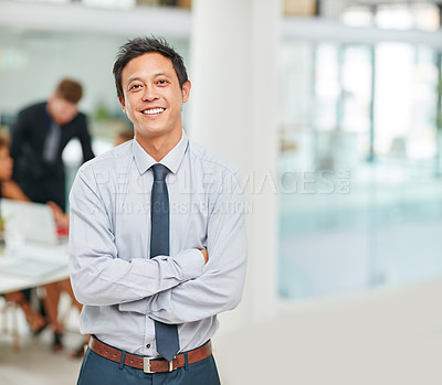 Buy stock photo Portrait of a smiling young businessman standing with his arms crossed in a modern office