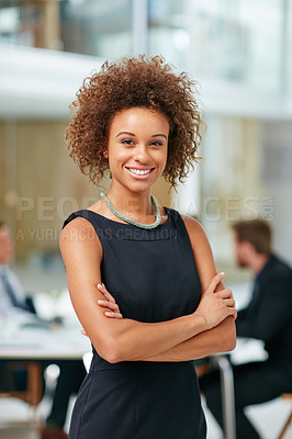 Buy stock photo Portrait of a smiling young businesswoman standing with her arms crossed in a modern office