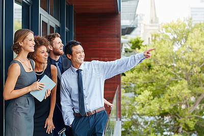 Buy stock photo Shot of a young businessman standing outside with his colleagues and pointing at something