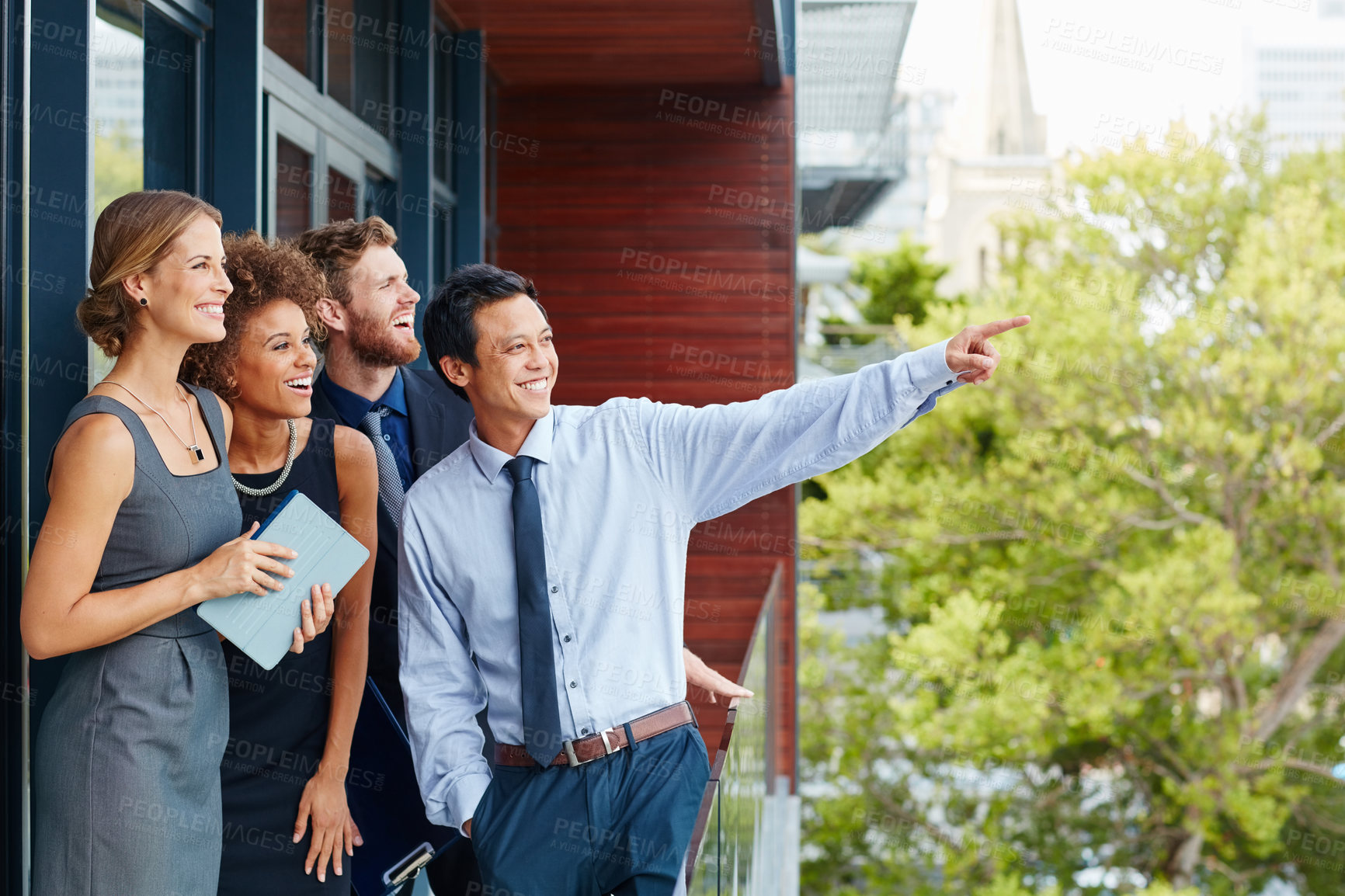 Buy stock photo Shot of a young businessman standing outside with his colleagues and pointing at something