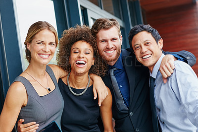 Buy stock photo Portrait of a group of happy young professionals embracing each other outside