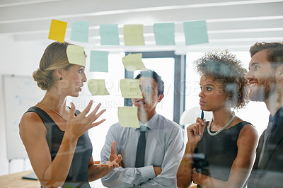 Buy stock photo Shot of coworkers using sticky notes against the wall during a brainstorming session