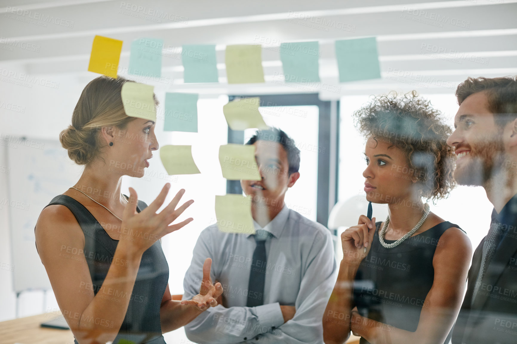 Buy stock photo Shot of coworkers using sticky notes against the wall during a brainstorming session