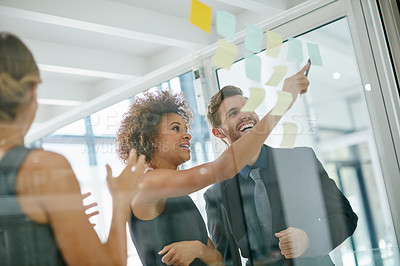 Buy stock photo Shot of coworkers using sticky notes against the wall during a brainstorming session