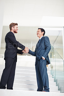 Buy stock photo Shot of two businessmen shaking hands in a modern office