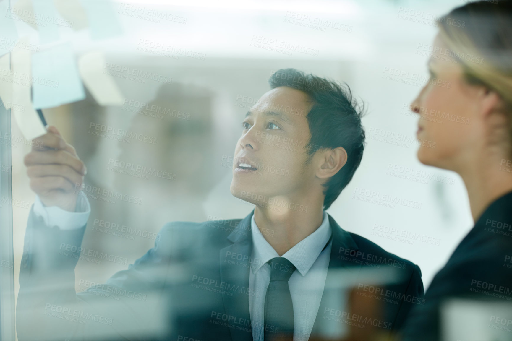 Buy stock photo Shot of coworkers using sticky notes against the wall during a brainstorming session