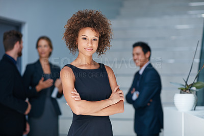 Buy stock photo Portrait of a young businesswoman standing in an office with colleagues in the background