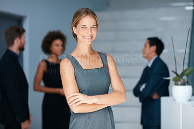 Buy stock photo Portrait of a young businesswoman standing in an office with colleagues in the background