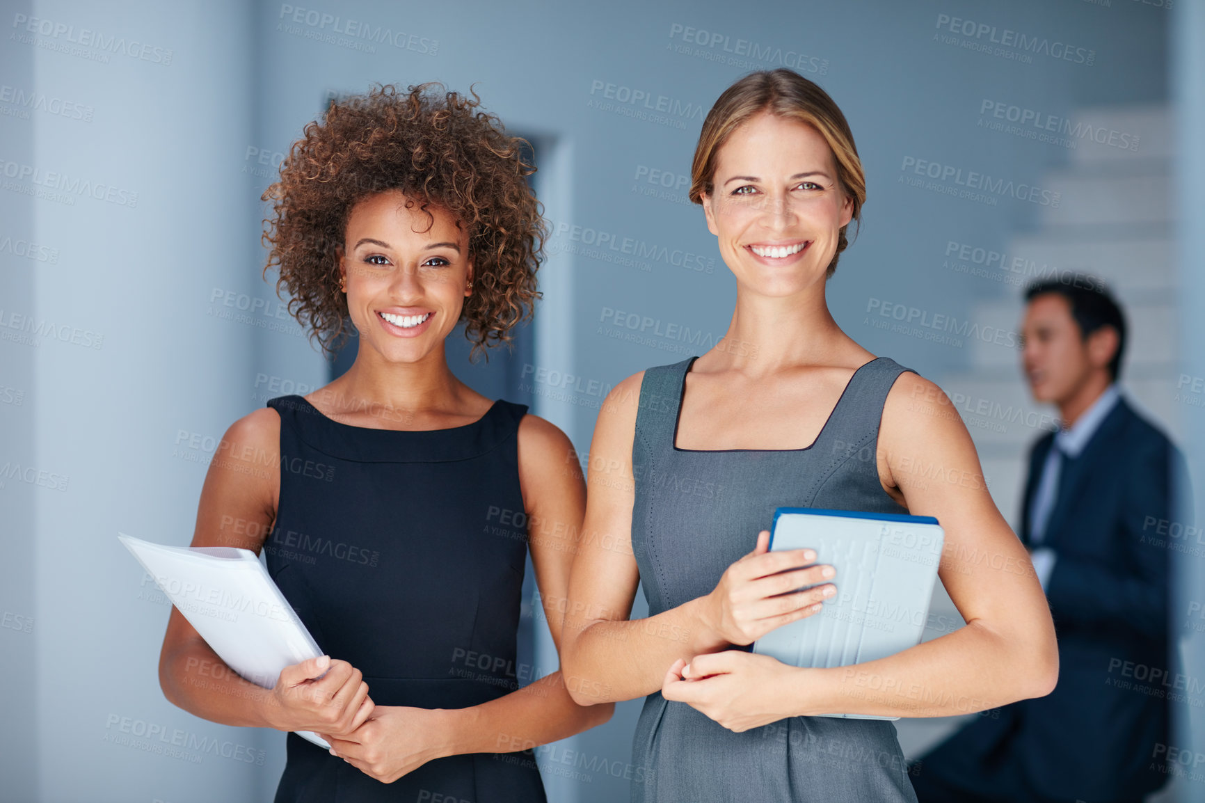 Buy stock photo Portrait of two businesswomen standing together in an office with colleagues in the background