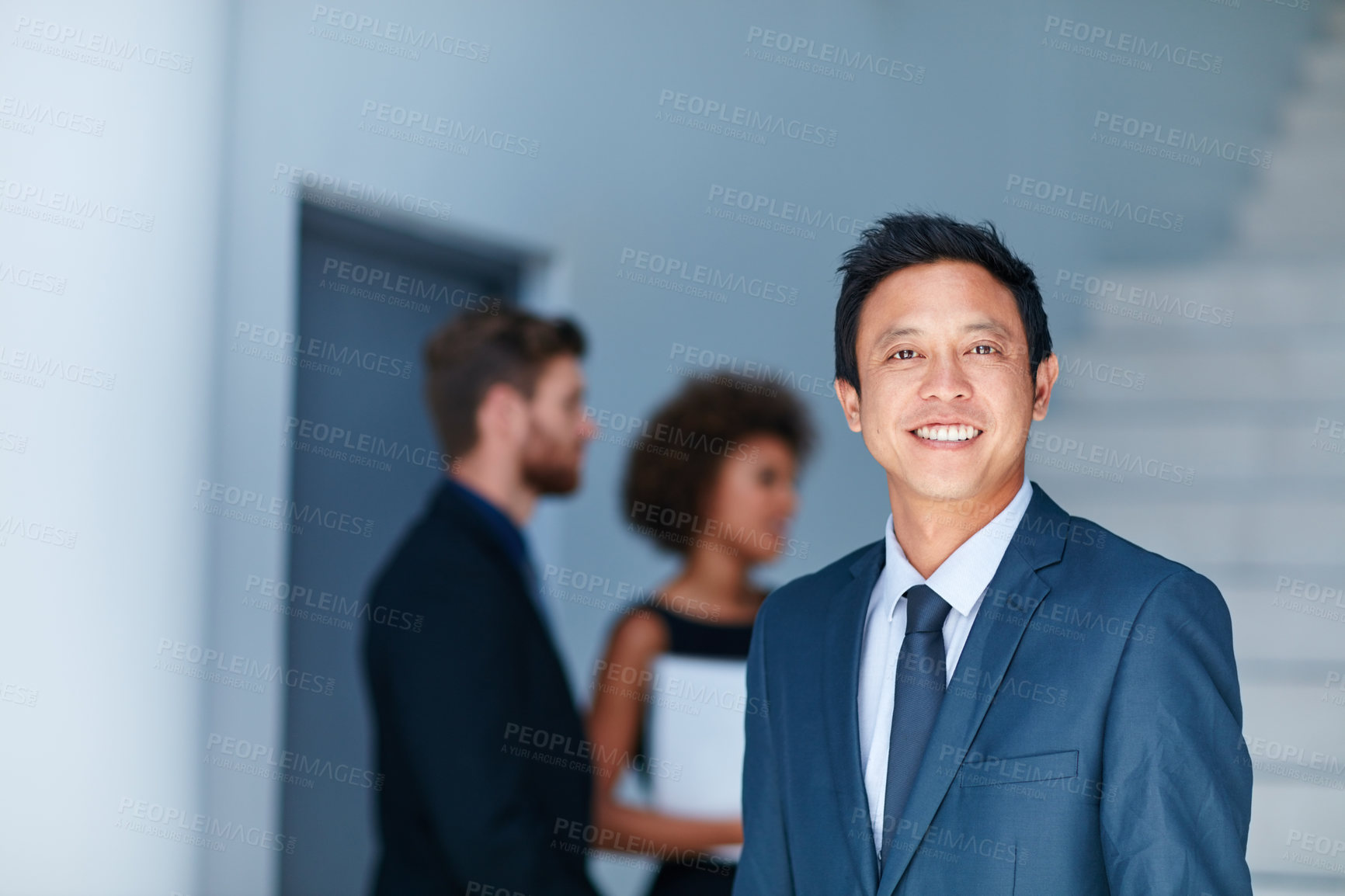 Buy stock photo Portrait of a young businessman standing in an office with colleagues in the background