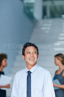 Buy stock photo Cropped shot of a young businessman standing in an office with colleagues in the background
