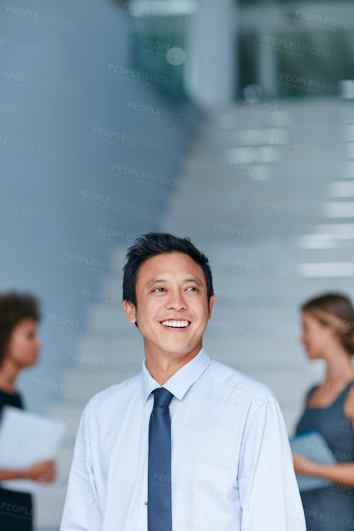 Buy stock photo Cropped shot of a young businessman standing in an office with colleagues in the background