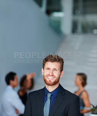Buy stock photo Portrait of a young businessman standing in an office with colleagues in the background
