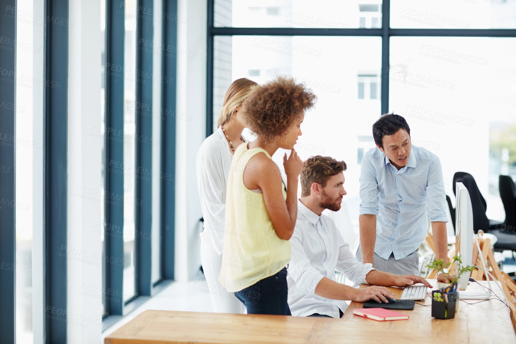 Buy stock photo Shot of a group of colleagues looking at something on a computer together in the office