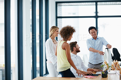 Buy stock photo Shot of a group of colleagues looking at something on a computer together in the office