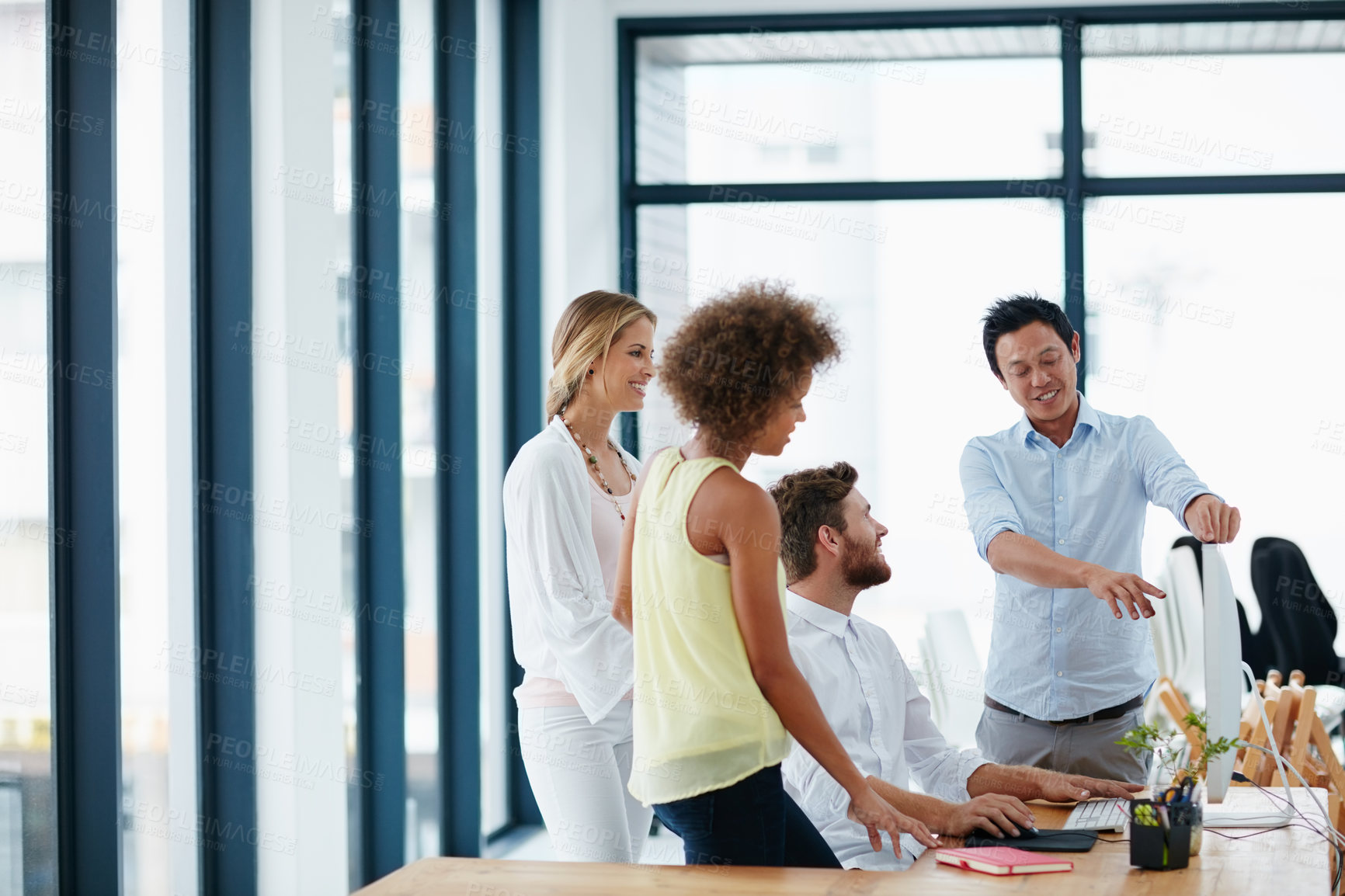 Buy stock photo Shot of a group of colleagues looking at something on a computer together in the office