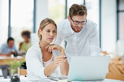 Buy stock photo Shot of a businesswoman and her male colleague working together on a laptop in their office