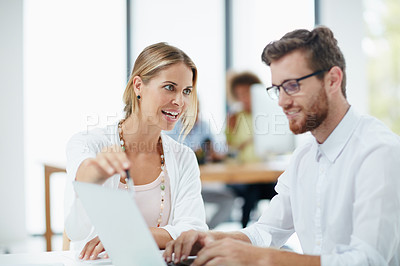 Buy stock photo Shot of a businesswoman and her male colleague working together on a laptop in their office
