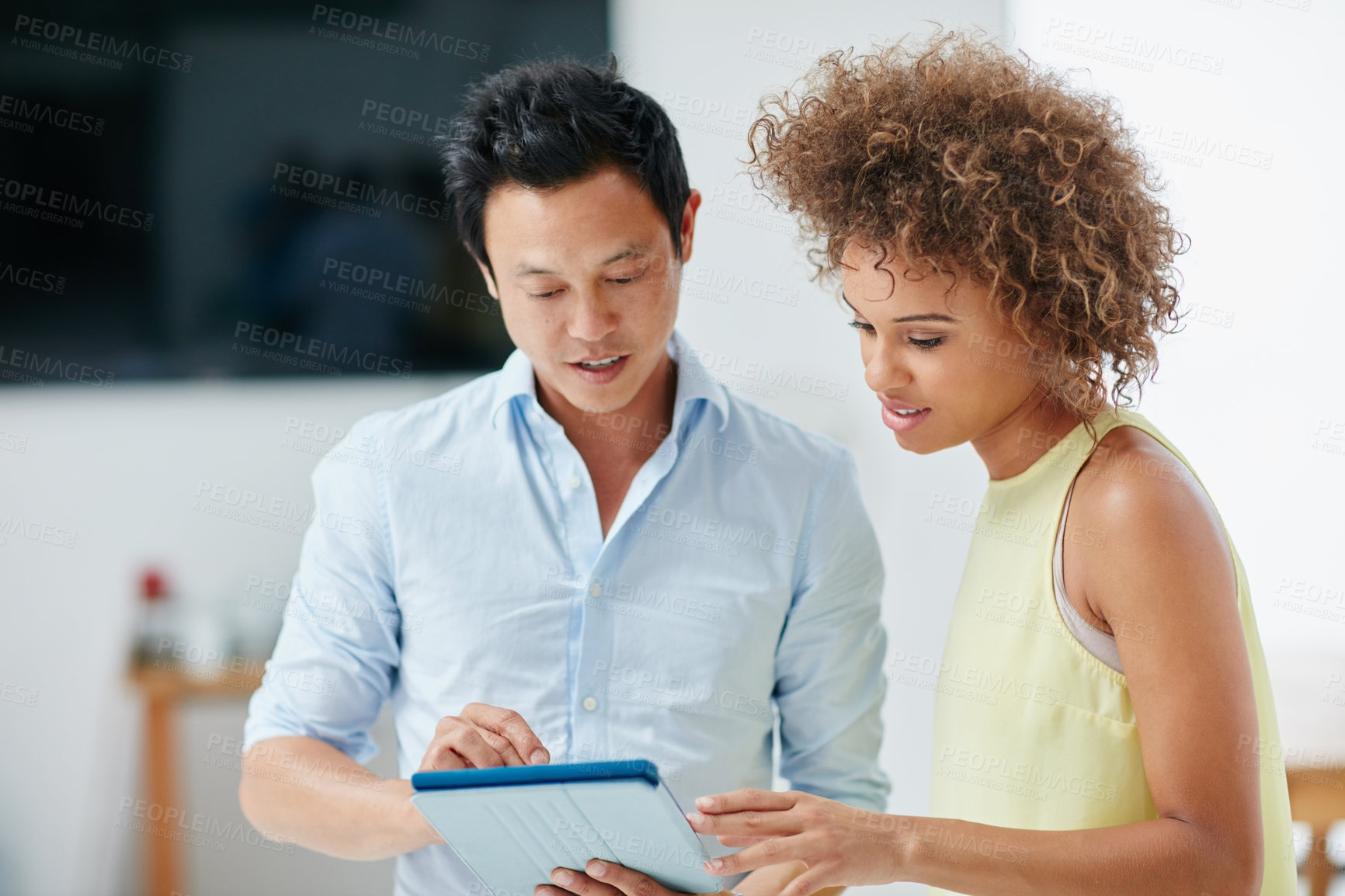 Buy stock photo Shot of a businessman and his female colleague looking at something together on a tablet in the office