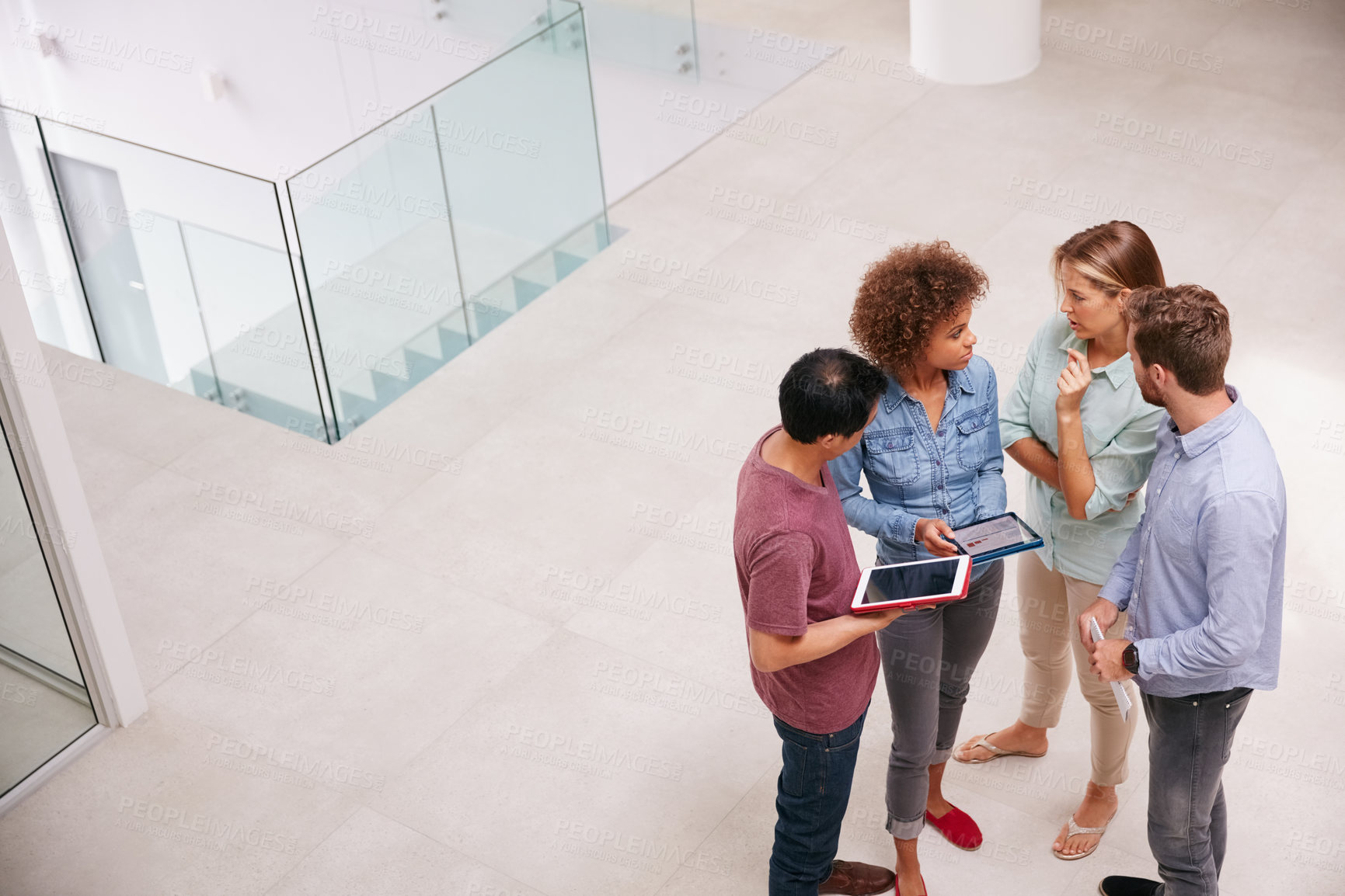 Buy stock photo High angle shot of a group of businesspeople talking together while standing in an office