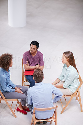 Buy stock photo High angle shot of a group of businesspeople talking together while sitting in a circle in an office