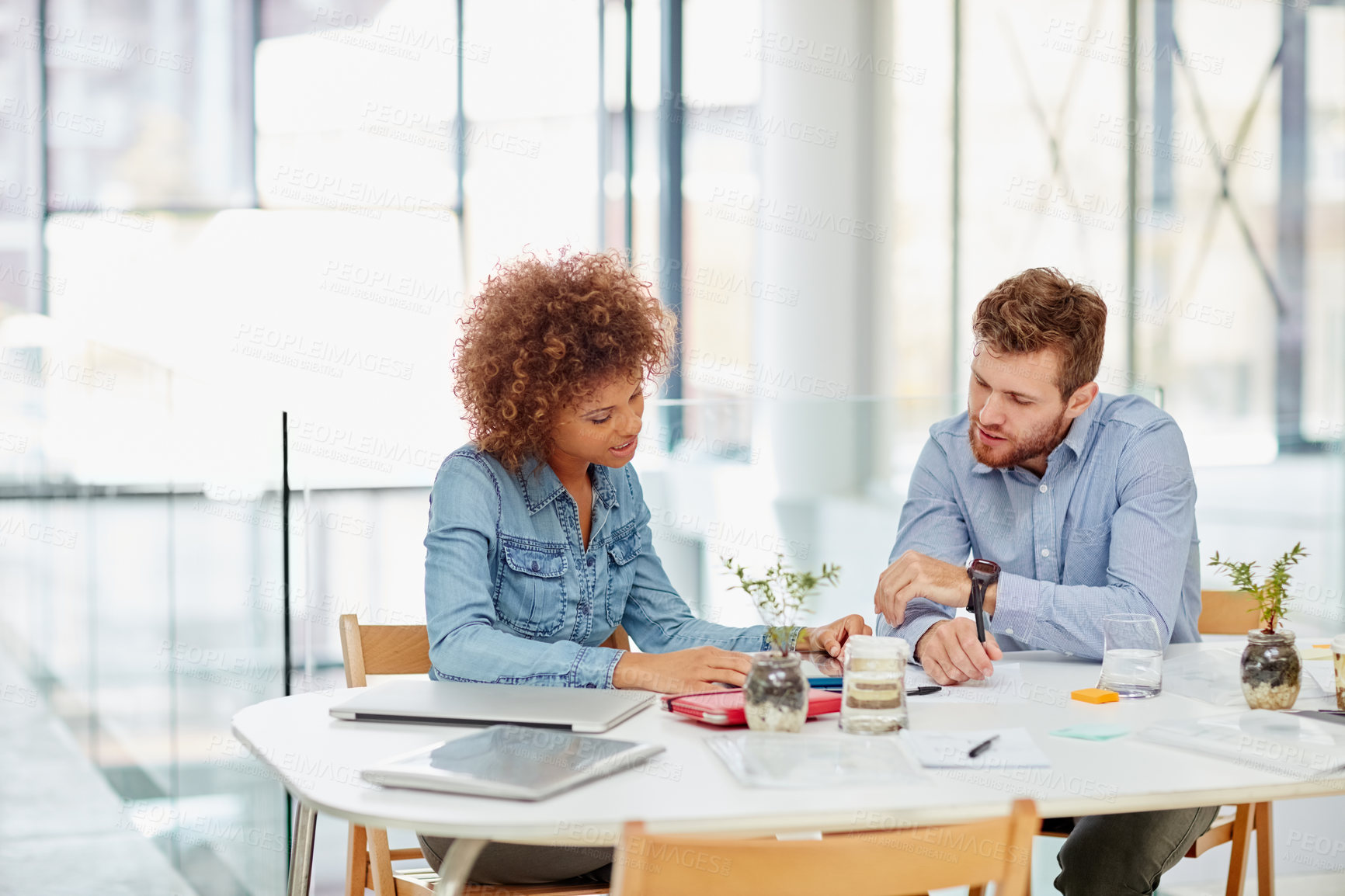 Buy stock photo Shot of two businesspeople talking together around a table in an office