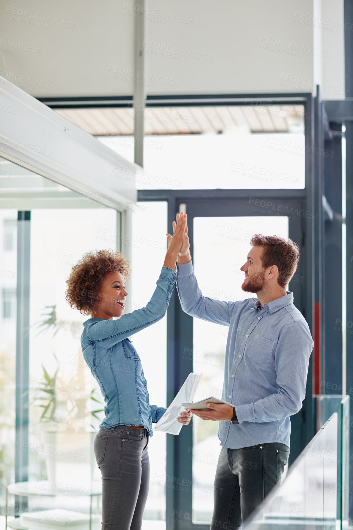 Buy stock photo Cropped shot of two colleagues high fiving each other other in an office