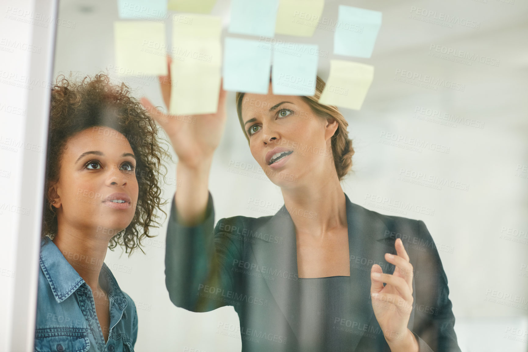 Buy stock photo Shot of coworkers using sticky notes against the wall during a brainstorming session