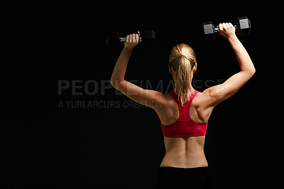 Buy stock photo Rearview shot of an attractive young woman working out with dumbbells