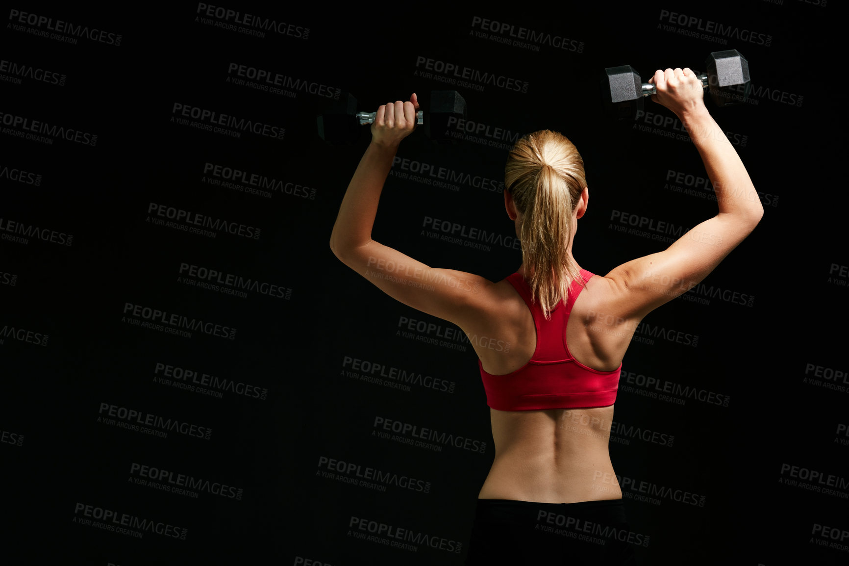 Buy stock photo Rearview shot of an attractive young woman working out with dumbbells