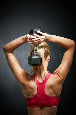 Buy stock photo Rearview shot of an attractive young woman working out with dumbbells