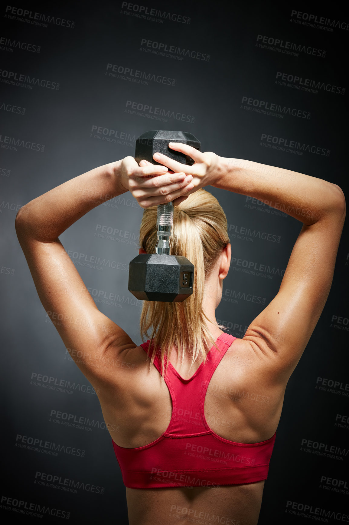 Buy stock photo Rearview shot of an attractive young woman working out with dumbbells