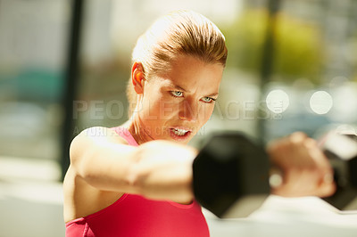 Buy stock photo Cropped shot of an attractive young woman working out with dumbbells