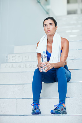 Buy stock photo Shot of a thoughtful young woman sitting on the stairs during her workout