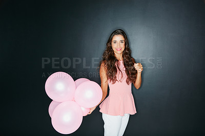 Buy stock photo Studio portrait of an attractive young woman holding balloons against a dark background