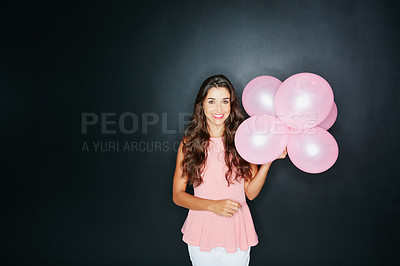 Buy stock photo Studio portrait of an attractive young woman holding balloons against a dark background