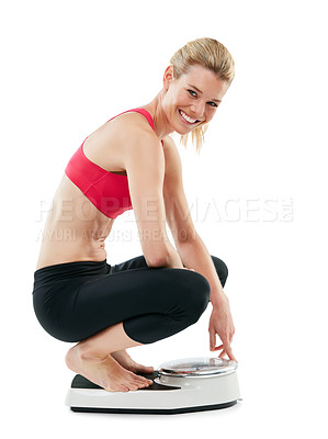 Buy stock photo Studio shot of a young woman weighing herself on a scale