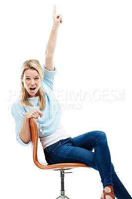 Buy stock photo Studio portrait of a young woman sitting on a chair and pointing upwards against a white background