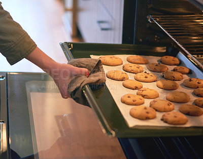 Buy stock photo Cropped shot of an unrecognizable woman taking cookies out of an oven