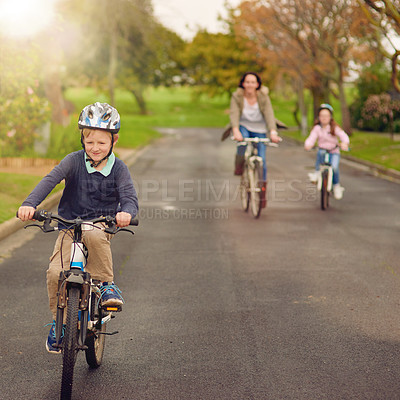 Buy stock photo Shot of a mother and her two young children riding their bicycles outside
