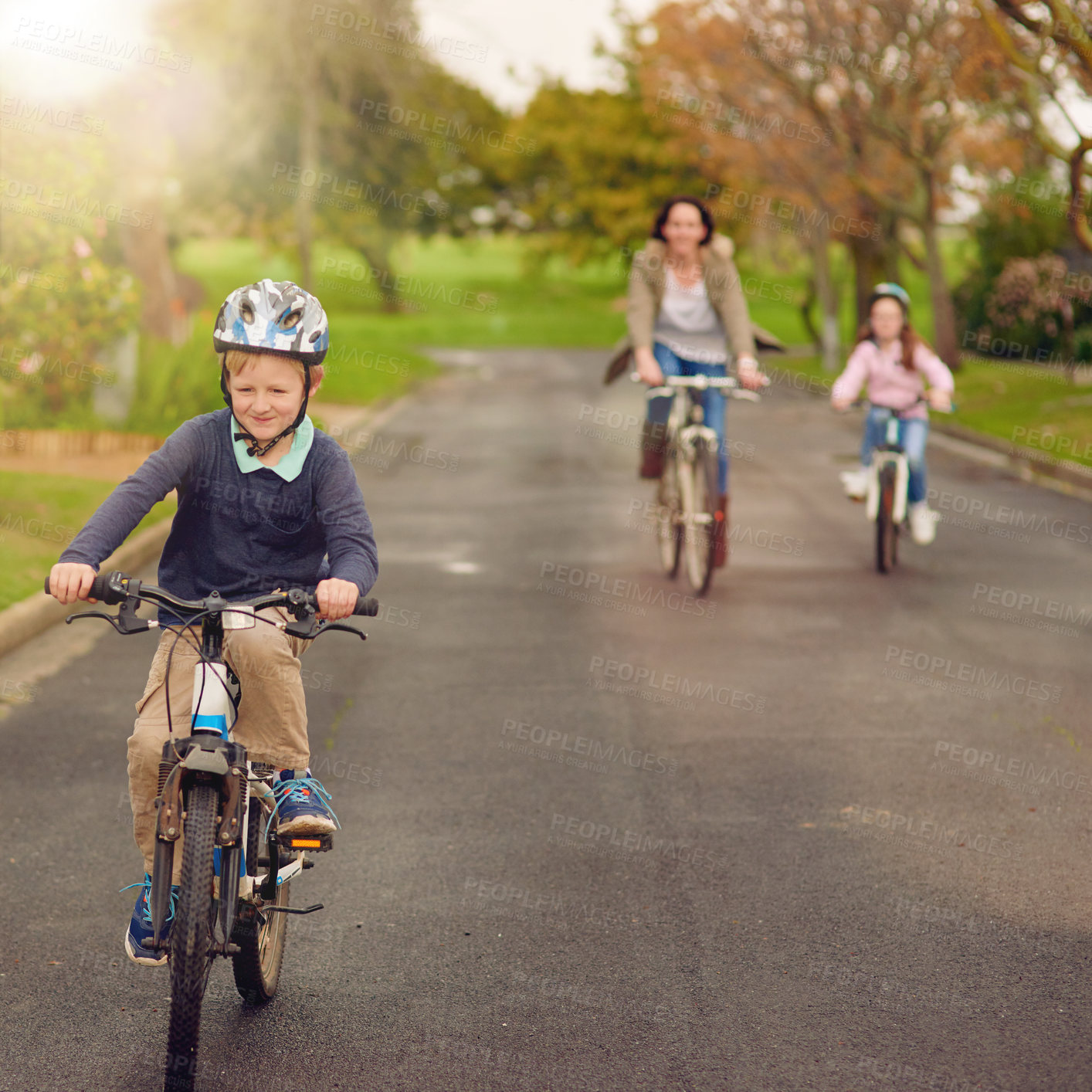 Buy stock photo Shot of a mother and her two young children riding their bicycles outside