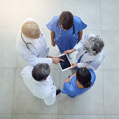 Buy stock photo High angle shot of medical practitioners looking at a patient's file on a digital tablet