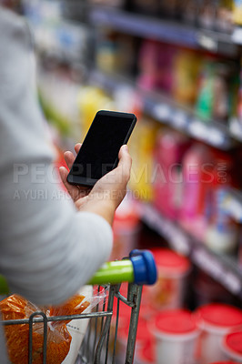 Buy stock photo Closeup shot of a woman checking her digital shopping list on her cellphone in a grocery store