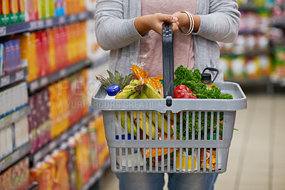 Buy stock photo Closeup shot of a woman holding a basket full of groceries in a supermarket