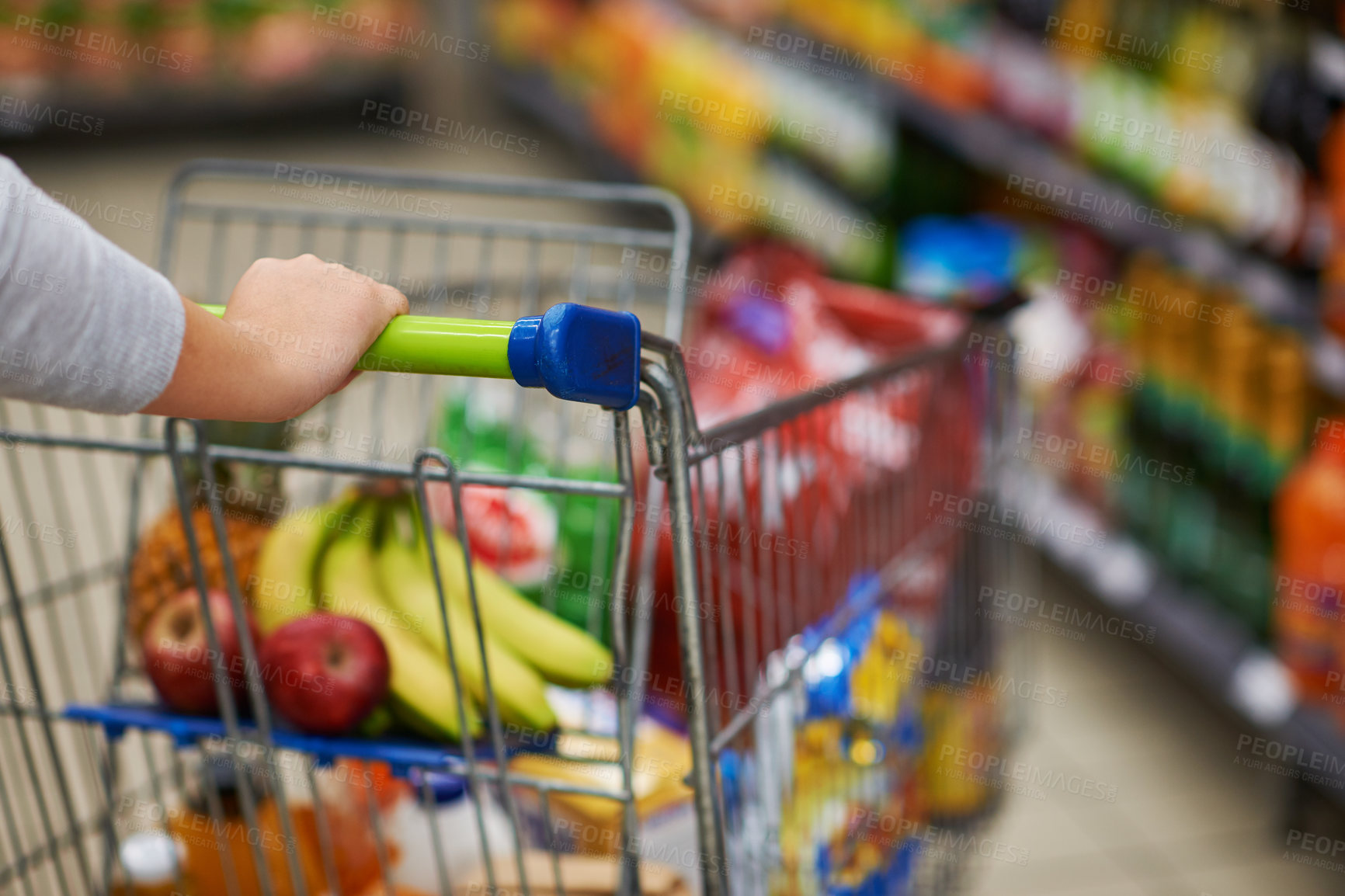 Buy stock photo Closeup shot of a woman pushing her trolley full of groceries in a supermarket