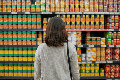 Buy stock photo Woman, grocery and canned food in supermarket for economy, purchase and products for nutrition. Female person, retail and shelf inside store with baked beans for shopping, vegetables and diet 